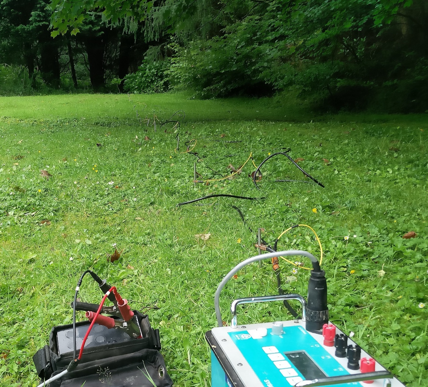 Resistivity electrodes and cable laid out in lines across a grass field.